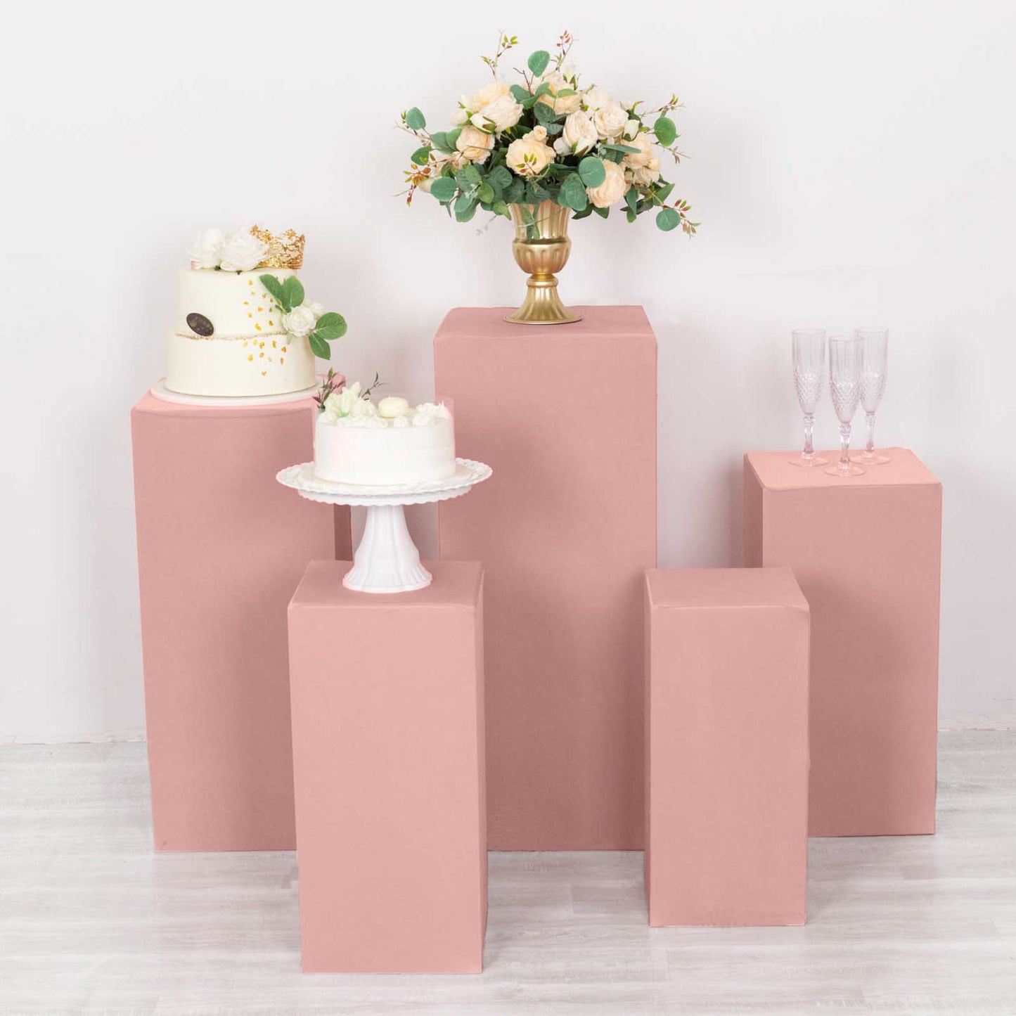 Dusty rose pedestal stand covers for events and displays.