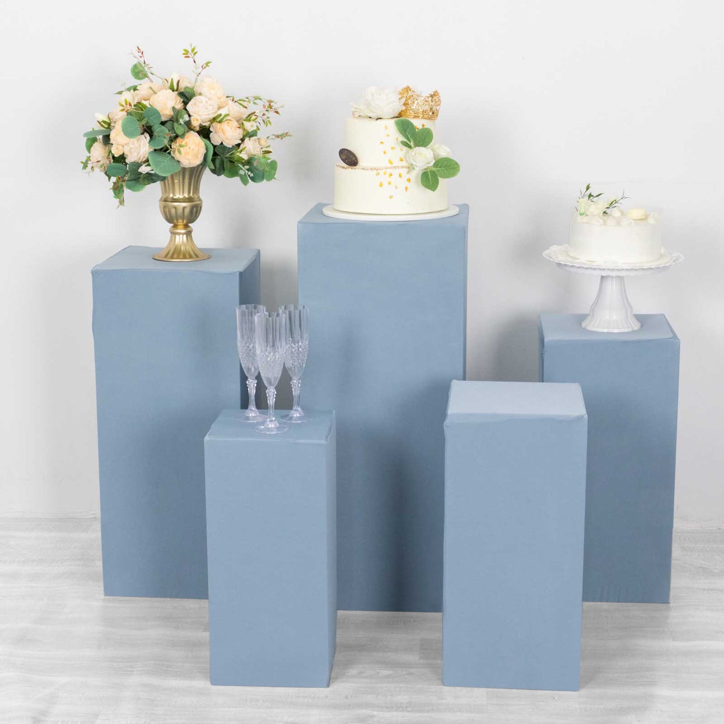 Dusty blue pedestal stand covers with floral and cake displays.
