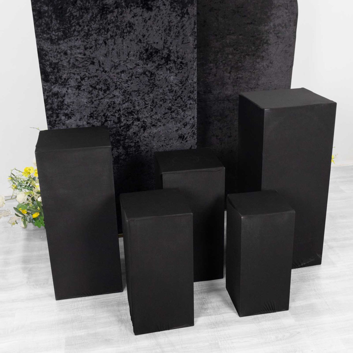 Set of 5 black spandex pedestal stand covers for events.