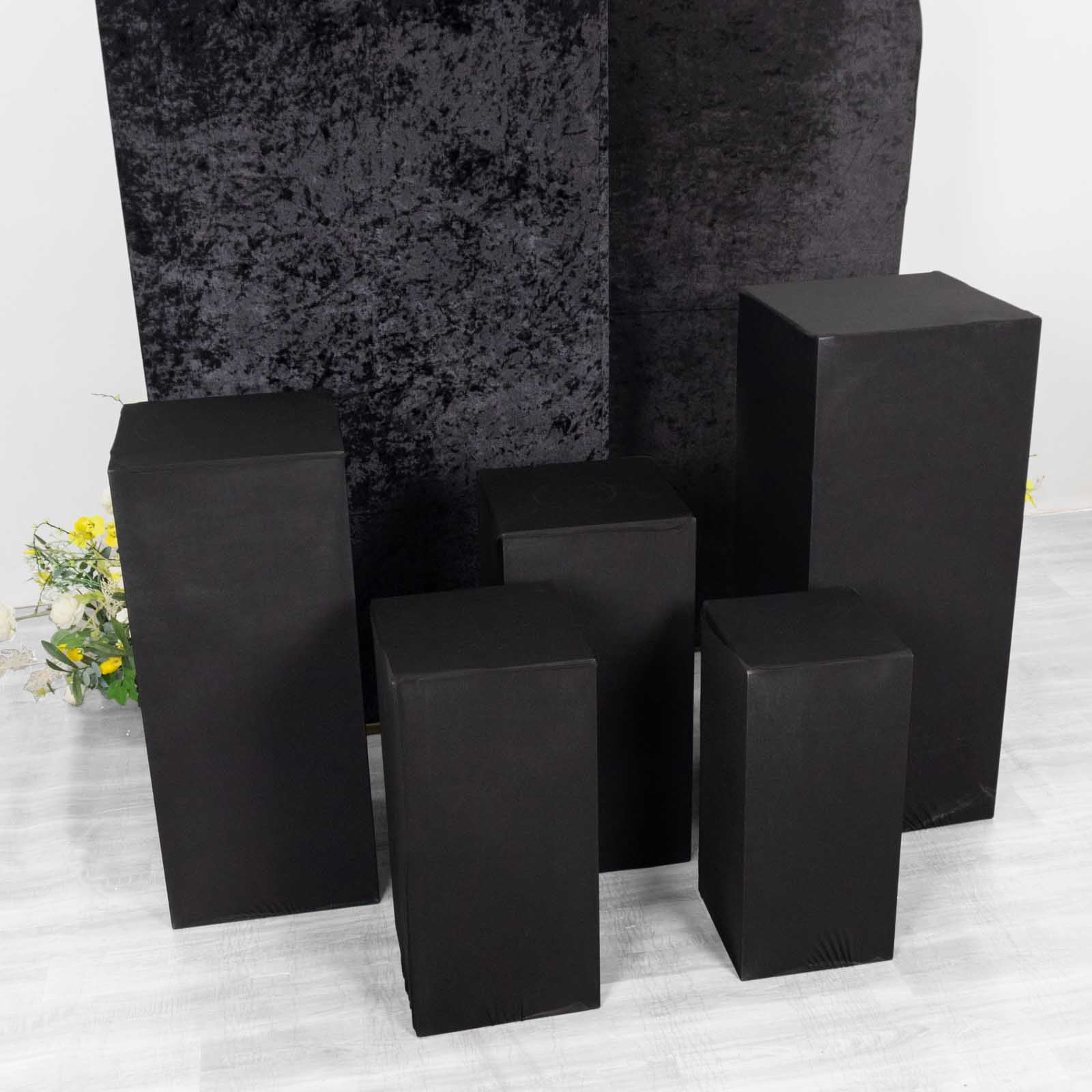 Set of 5 black spandex pedestal stand covers for events.