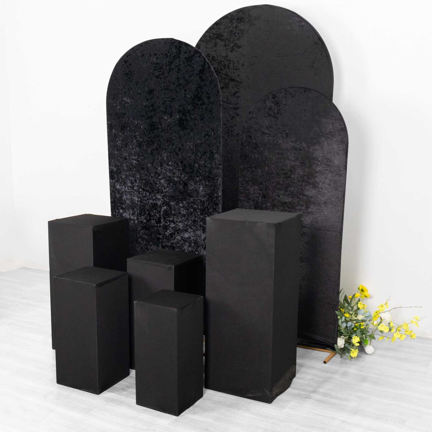 Set of 5 black spandex pedestal stand covers for events.
