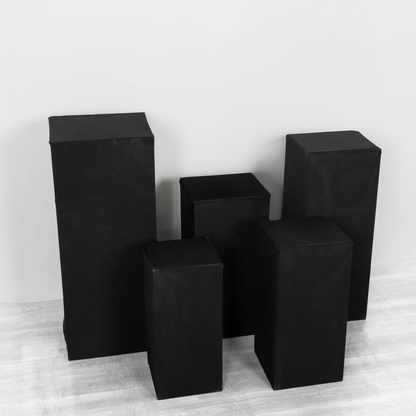 Set of 5 black spandex pedestal stand covers for events.