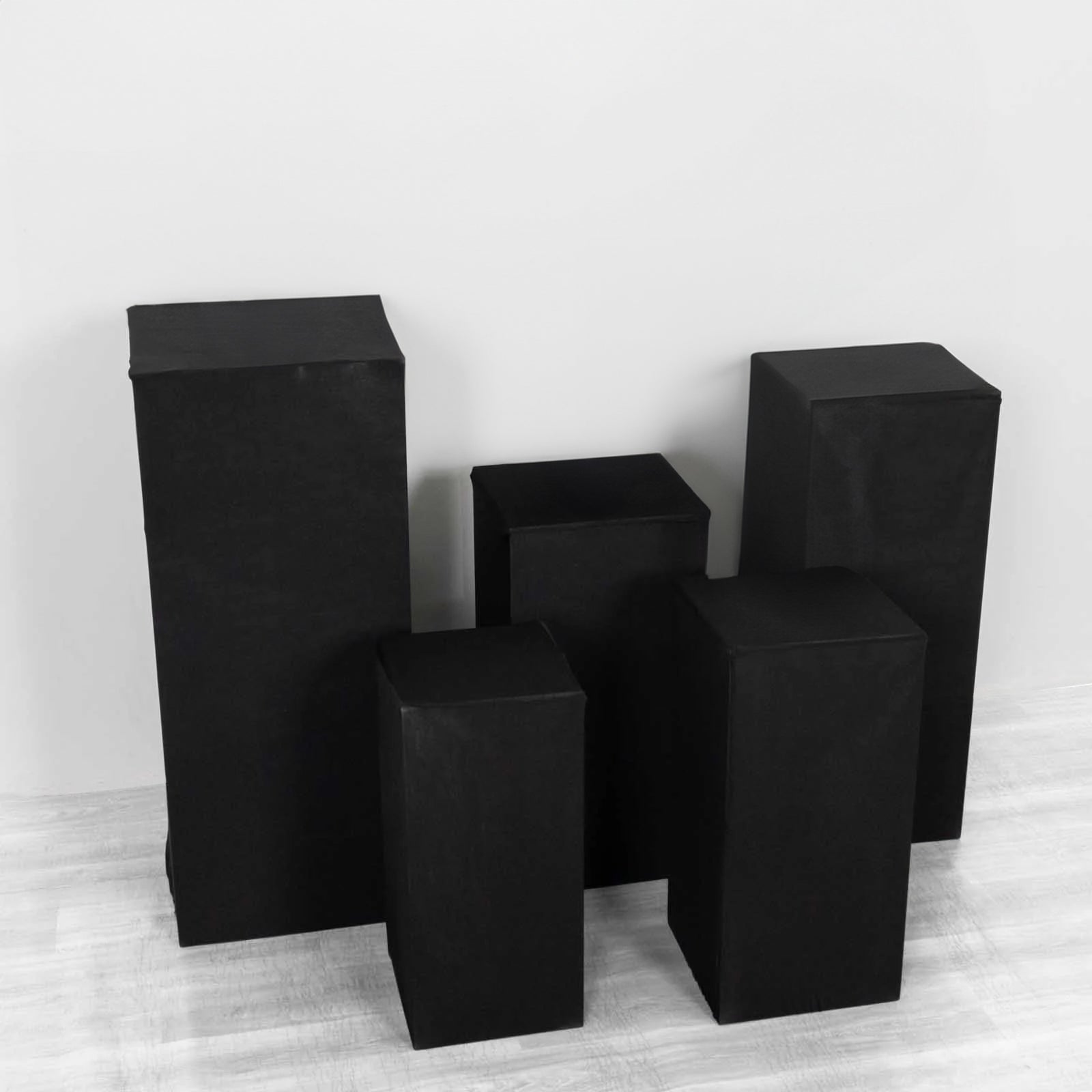 Set of 5 black spandex pedestal stand covers for events.