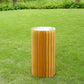 Gold cylinder display column stand with top plate on a grassy background.