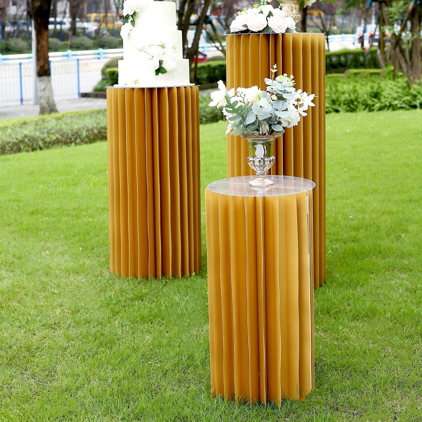 Gold display column stand for showcasing decor and floral arrangements.