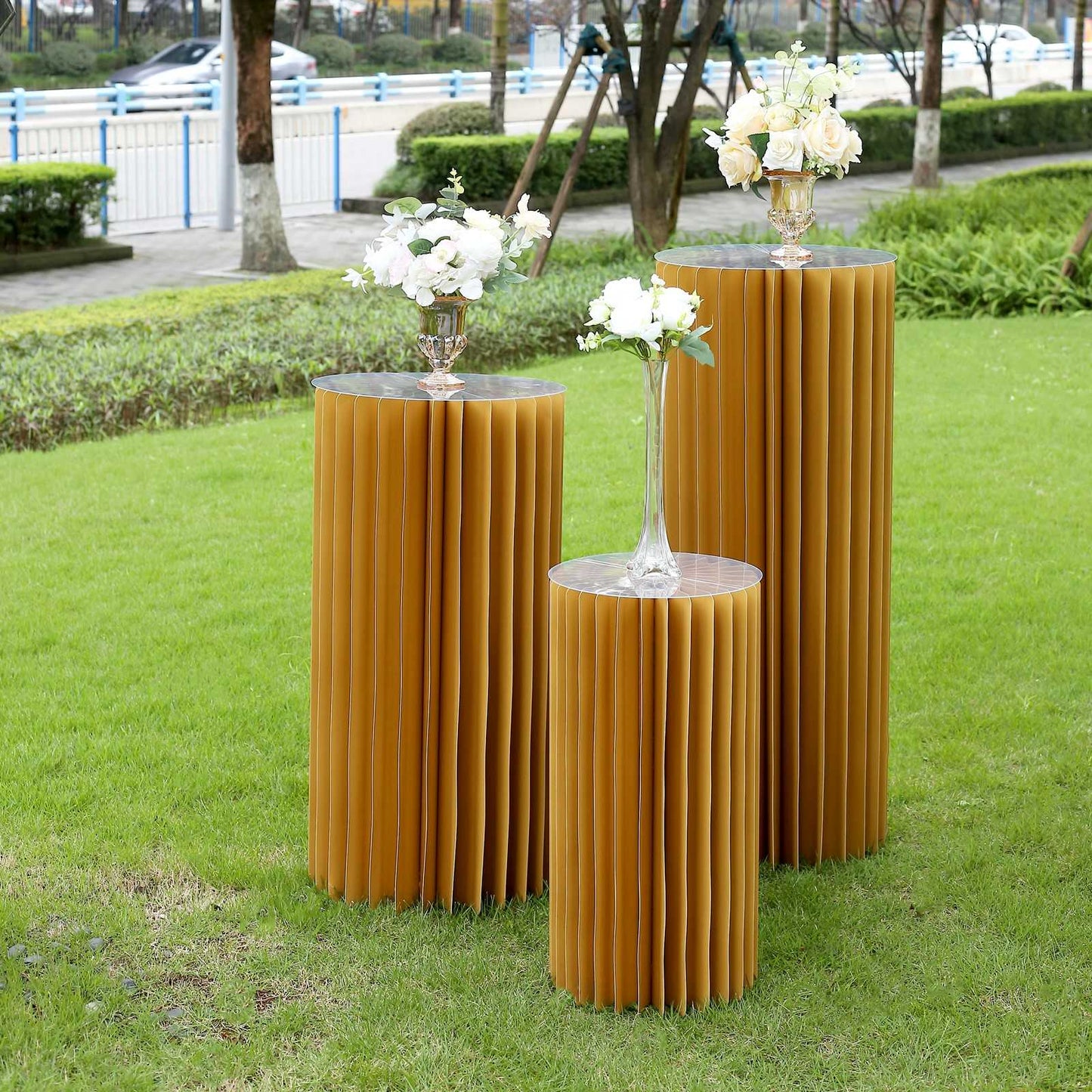 Gold cylinder display column stand, pillar pedestal with top plate in outdoor setting.