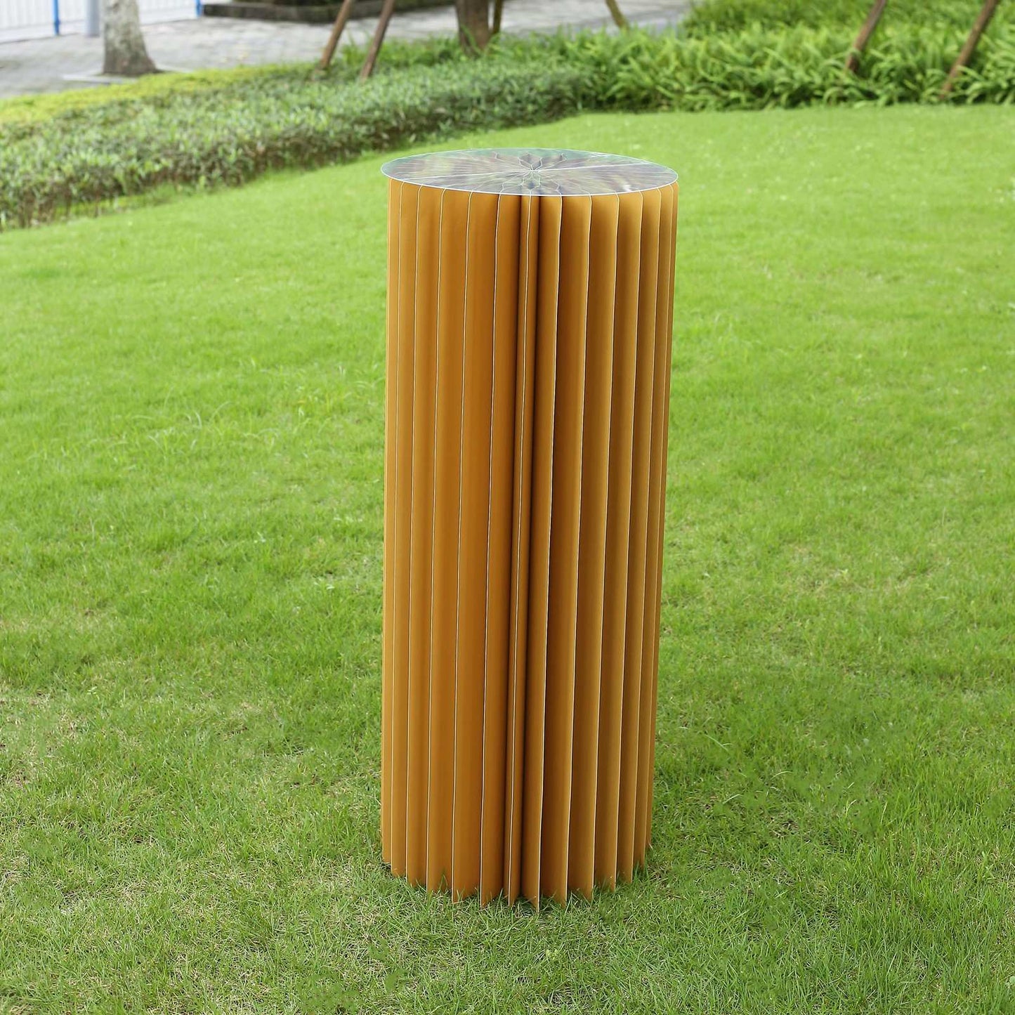 Gold display column stand with top plate on grass.