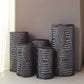 Black sequin mesh cylinder pedestal stand covers with geometric embroidery.