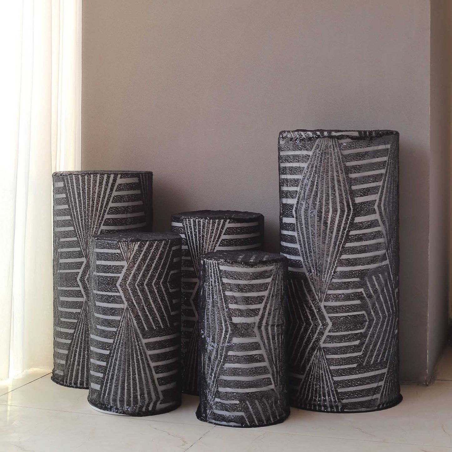 Black sequin mesh cylinder pedestal stand covers with geometric embroidery.