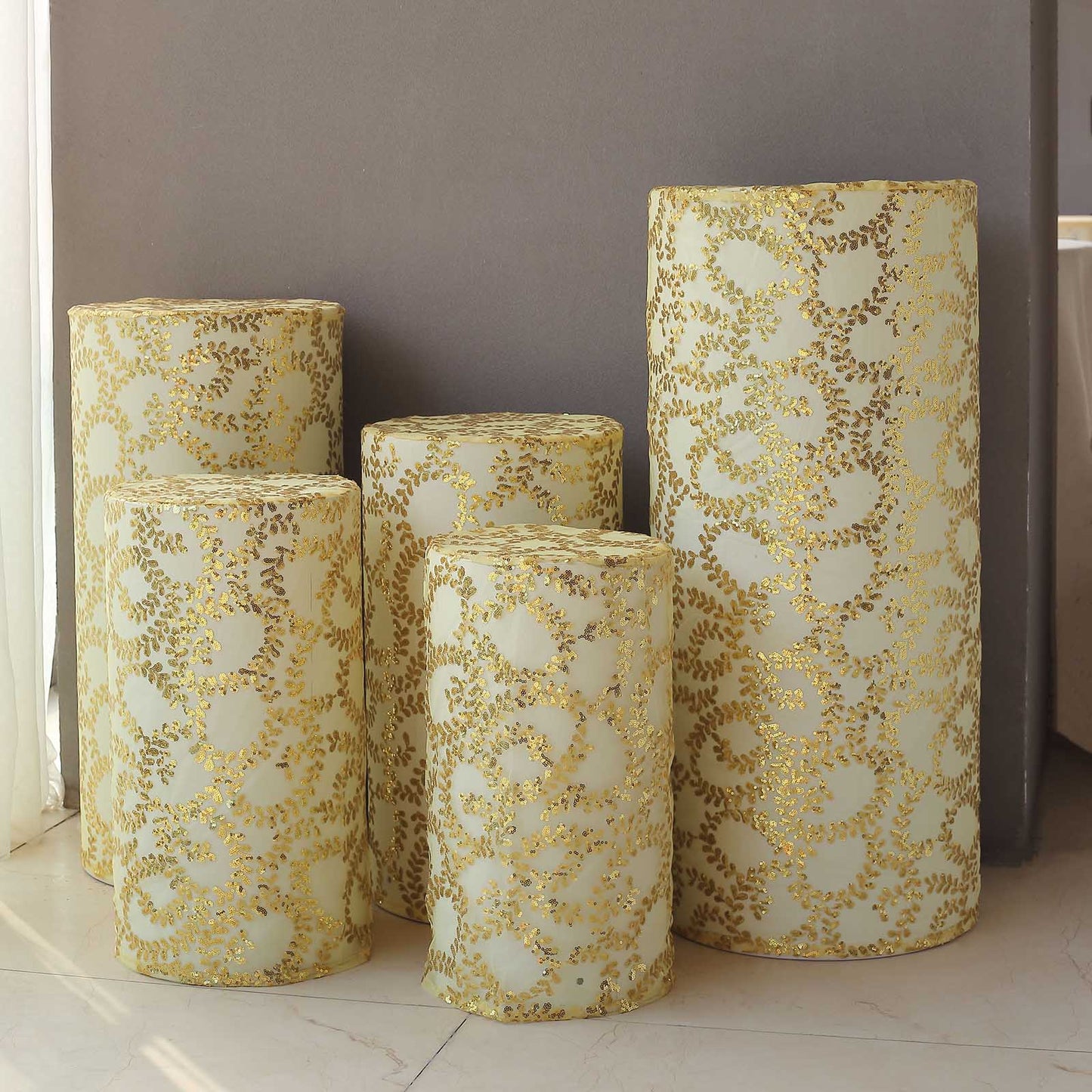 Gold sequin mesh pedestal stand covers with leaf vine embroidery.