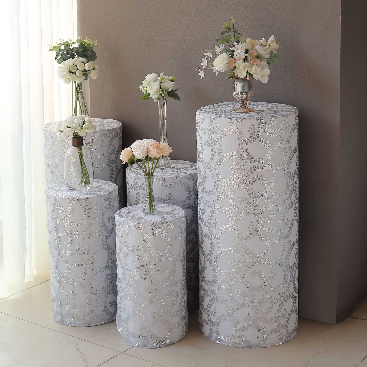 Silver sequin mesh cylinder pedestal stand covers with leaf vine embroidery.