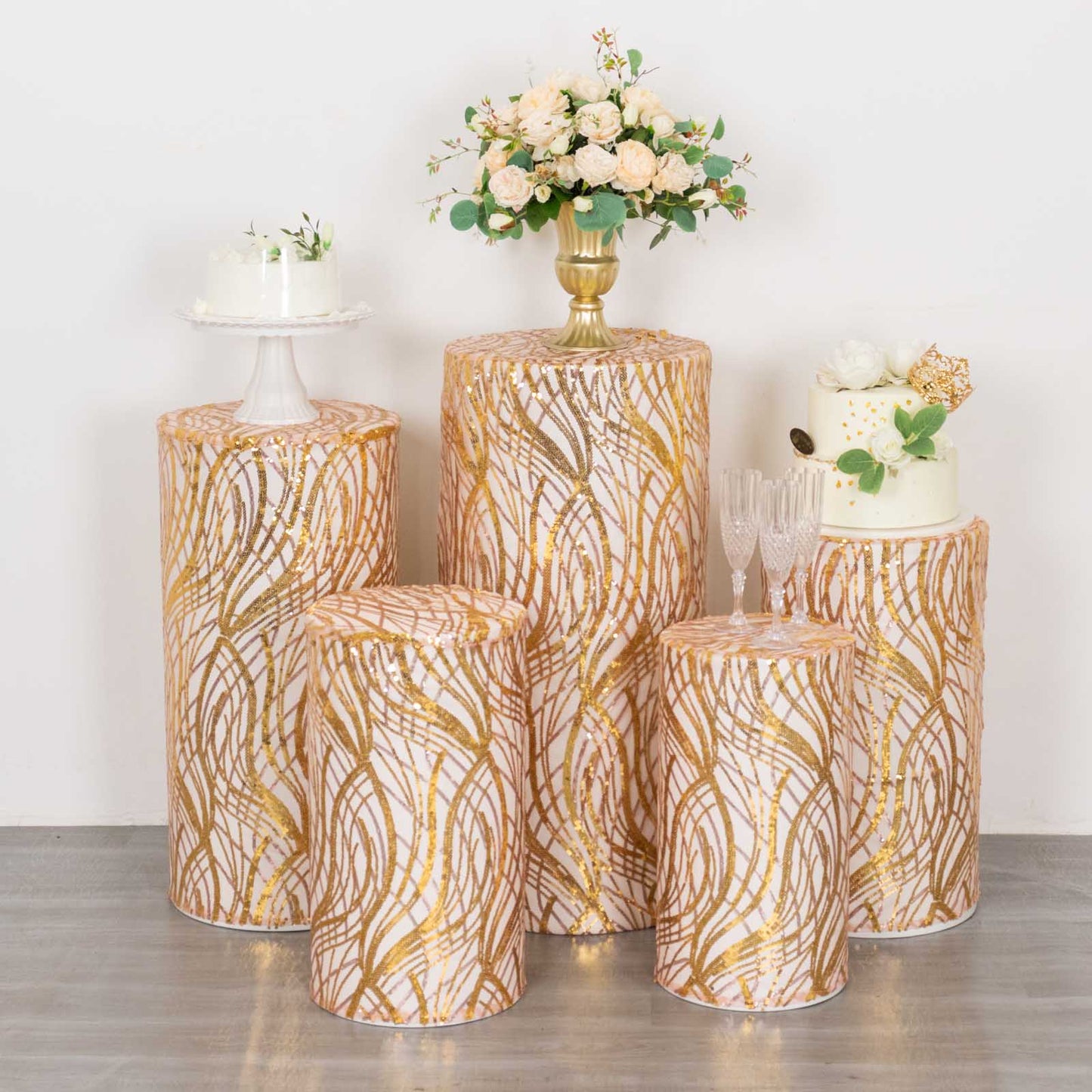 Set of 5 rose gold wave mesh cylinder pedestal stand covers with sequins.