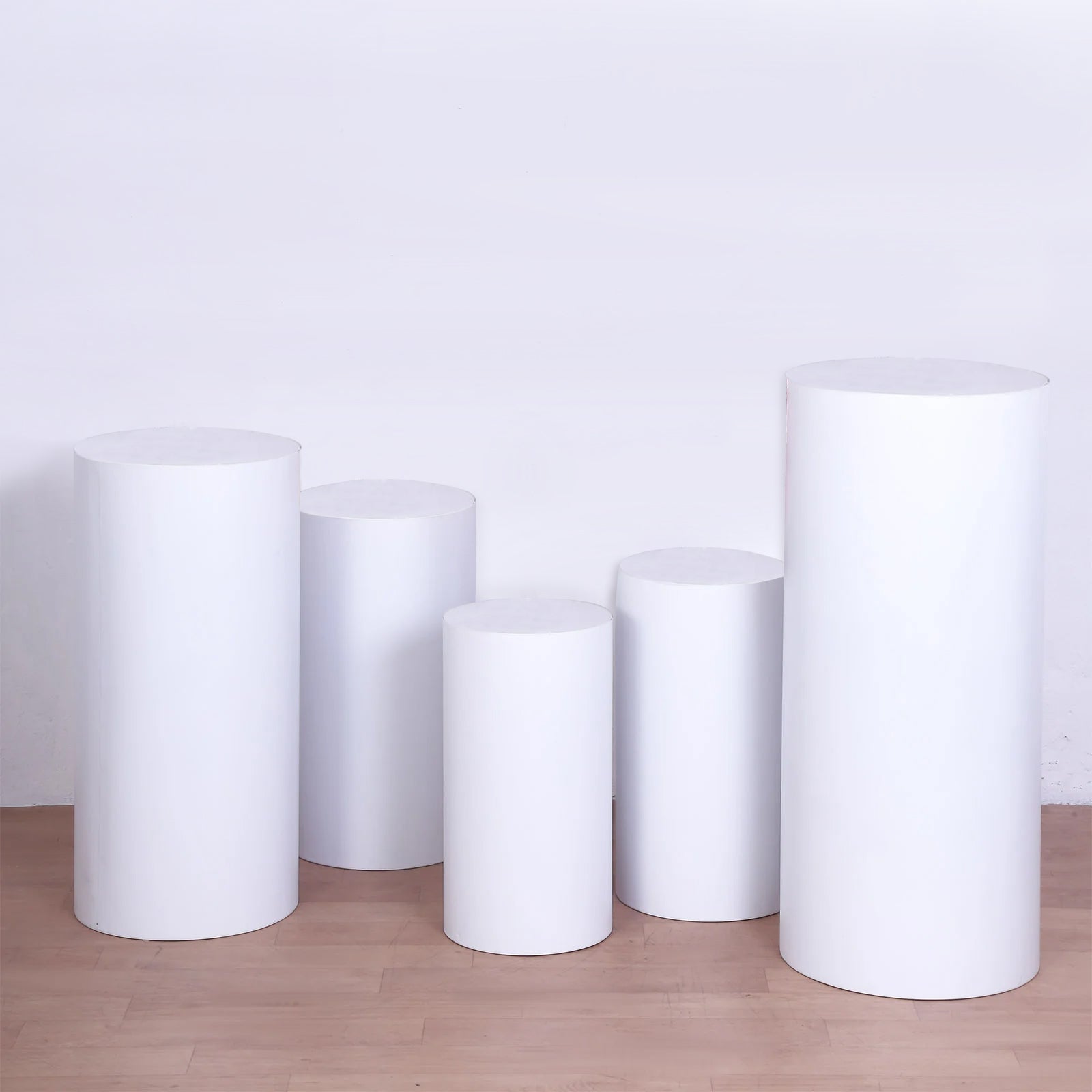 Set of 5 white metal cylinder pillar prop stands for wedding display.