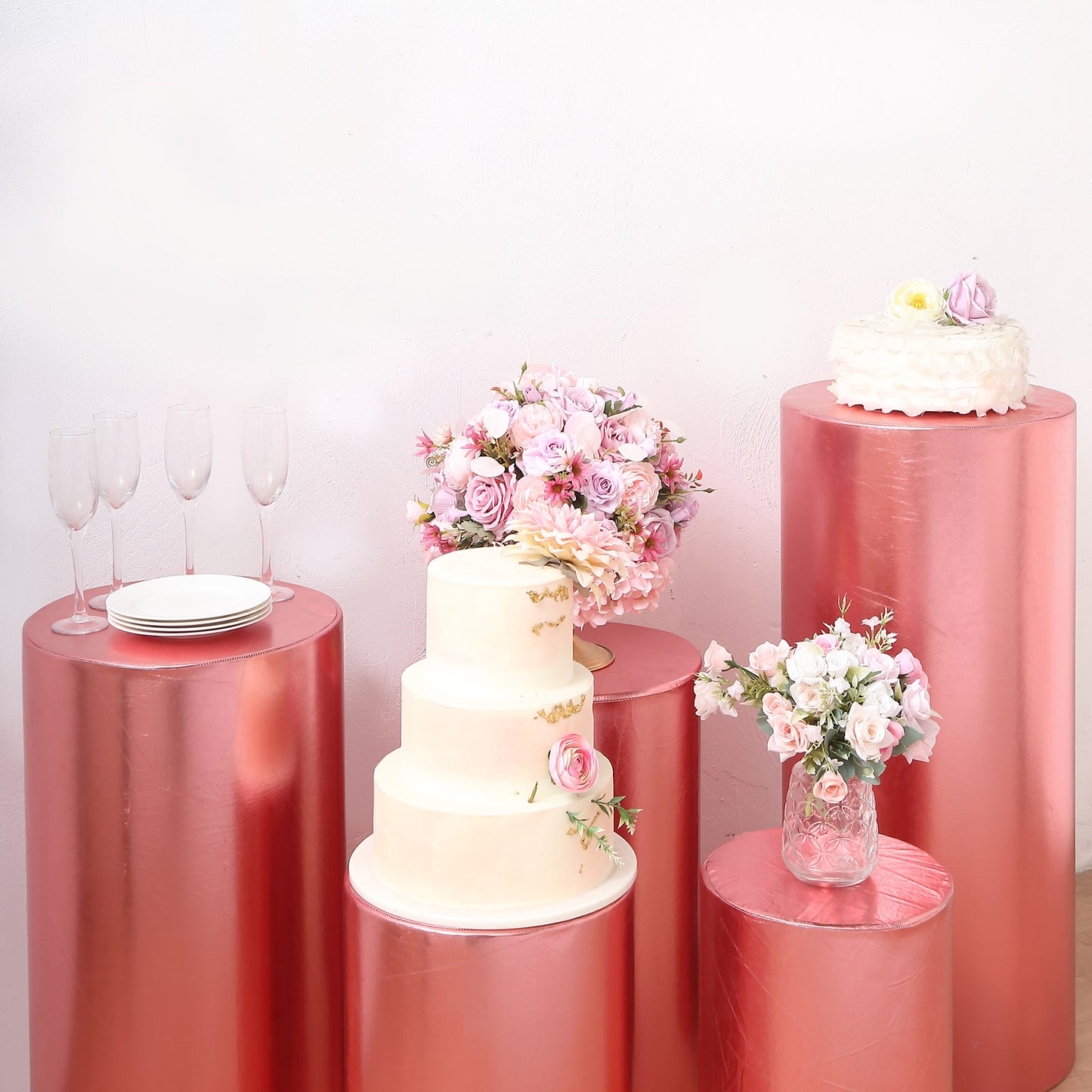 Metallic rose gold pedestal stand covers with floral decorations and tableware.