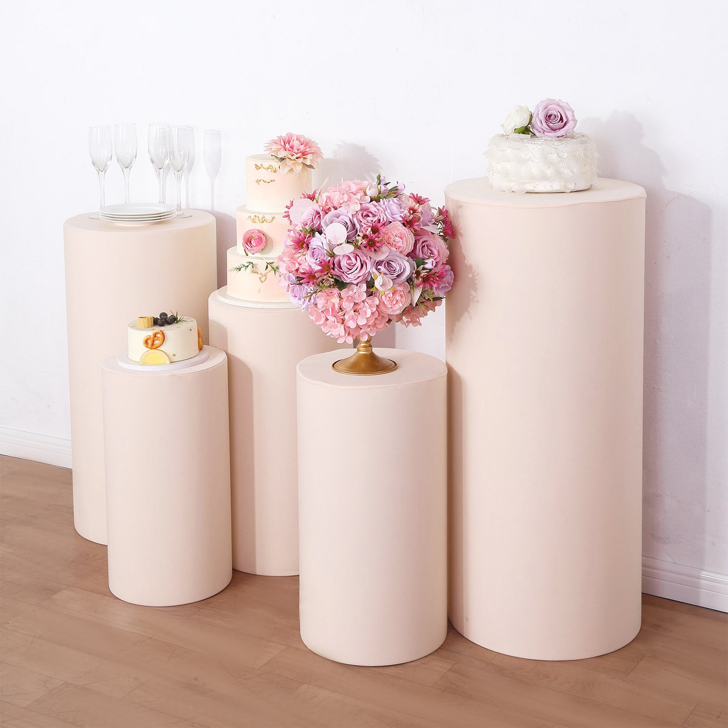 Blush spandex cylinder pedestal stand covers for event decor.