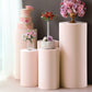 Blush spandex cylinder pedestal stand covers for decorative display.