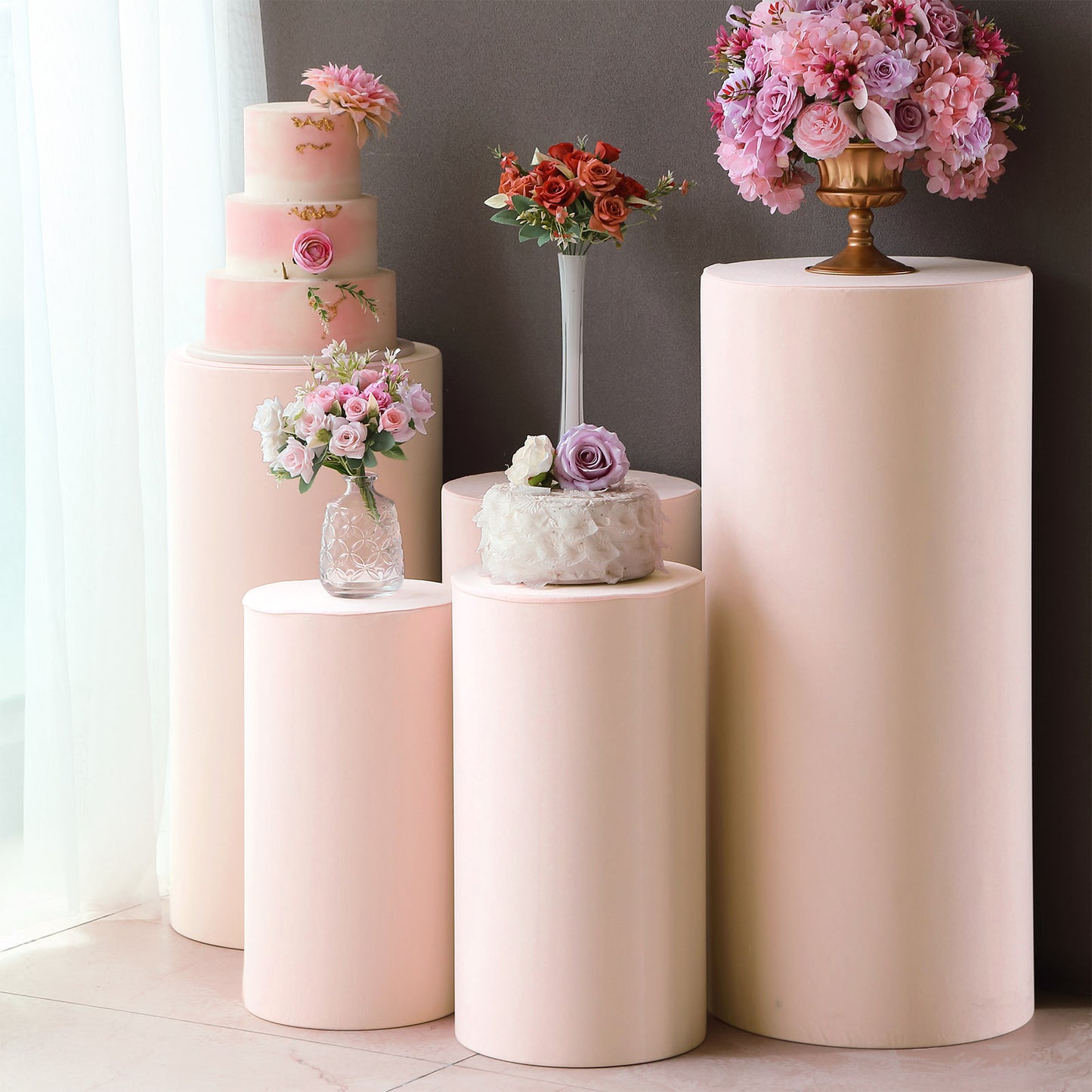 Blush spandex cylinder pedestal stand covers for decorative display.