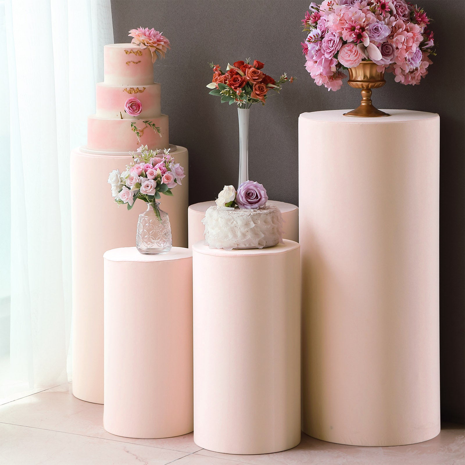 Blush spandex cylinder pedestal stand covers for decorative display.