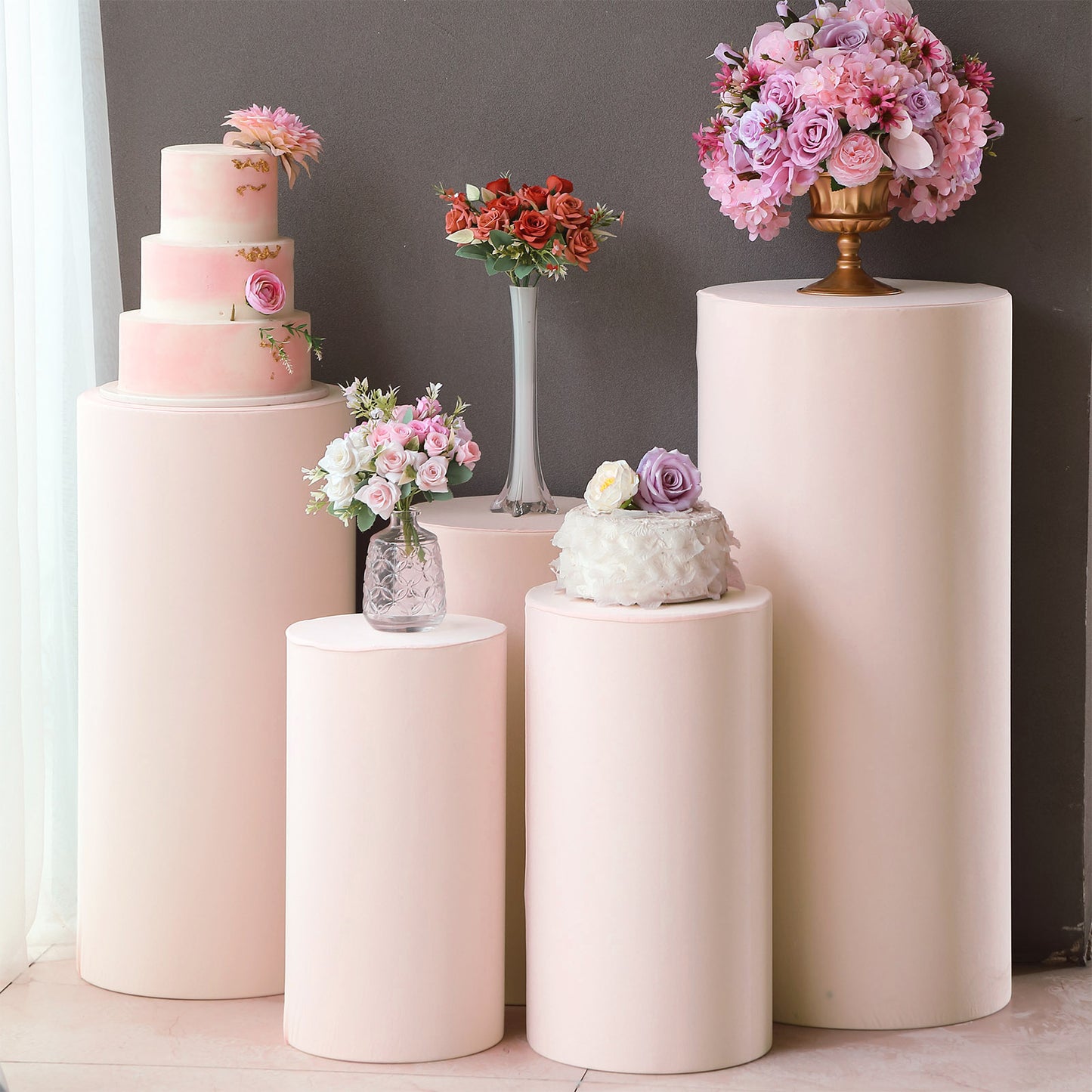Blush spandex cylinder pedestal stand covers for events and displays.
