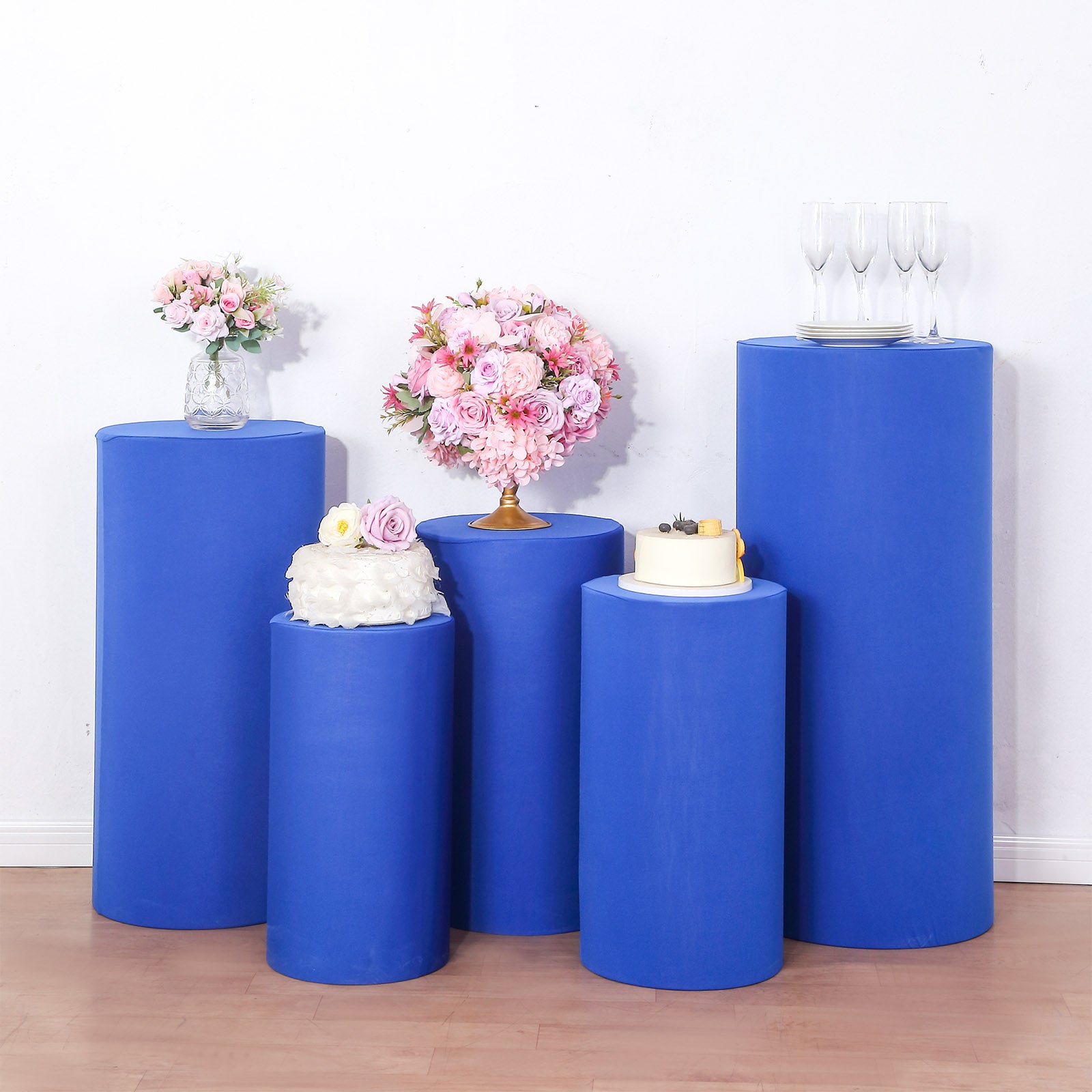 Royal blue spandex pedestal stand covers on display with decorative items.