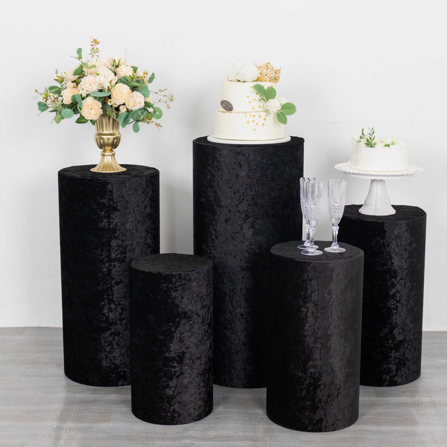 Set of 5 black crushed velvet pedestal stand covers for events.