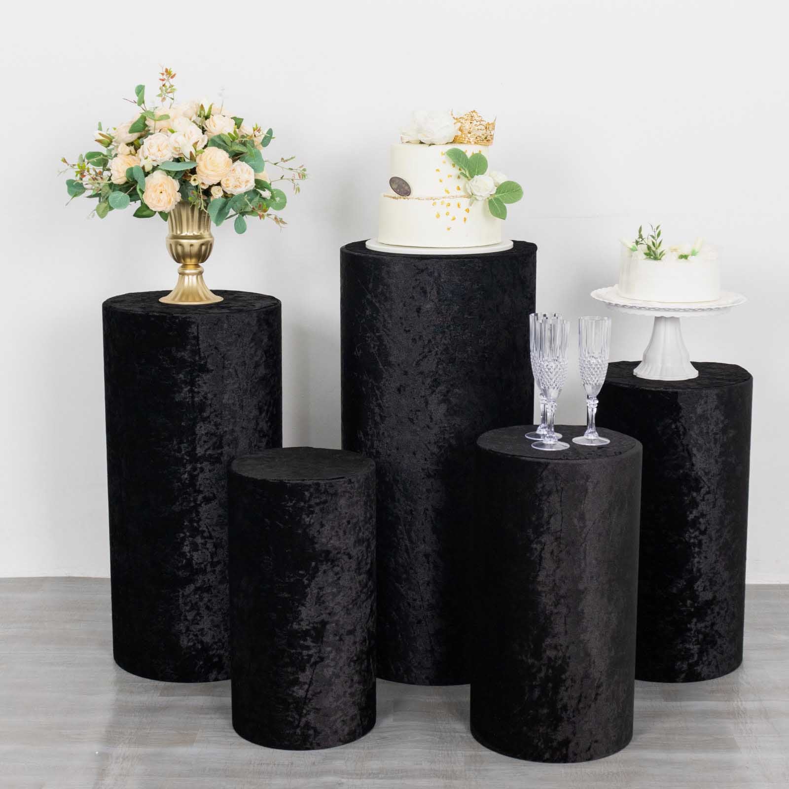 Set of 5 black crushed velvet pedestal stand covers for events.