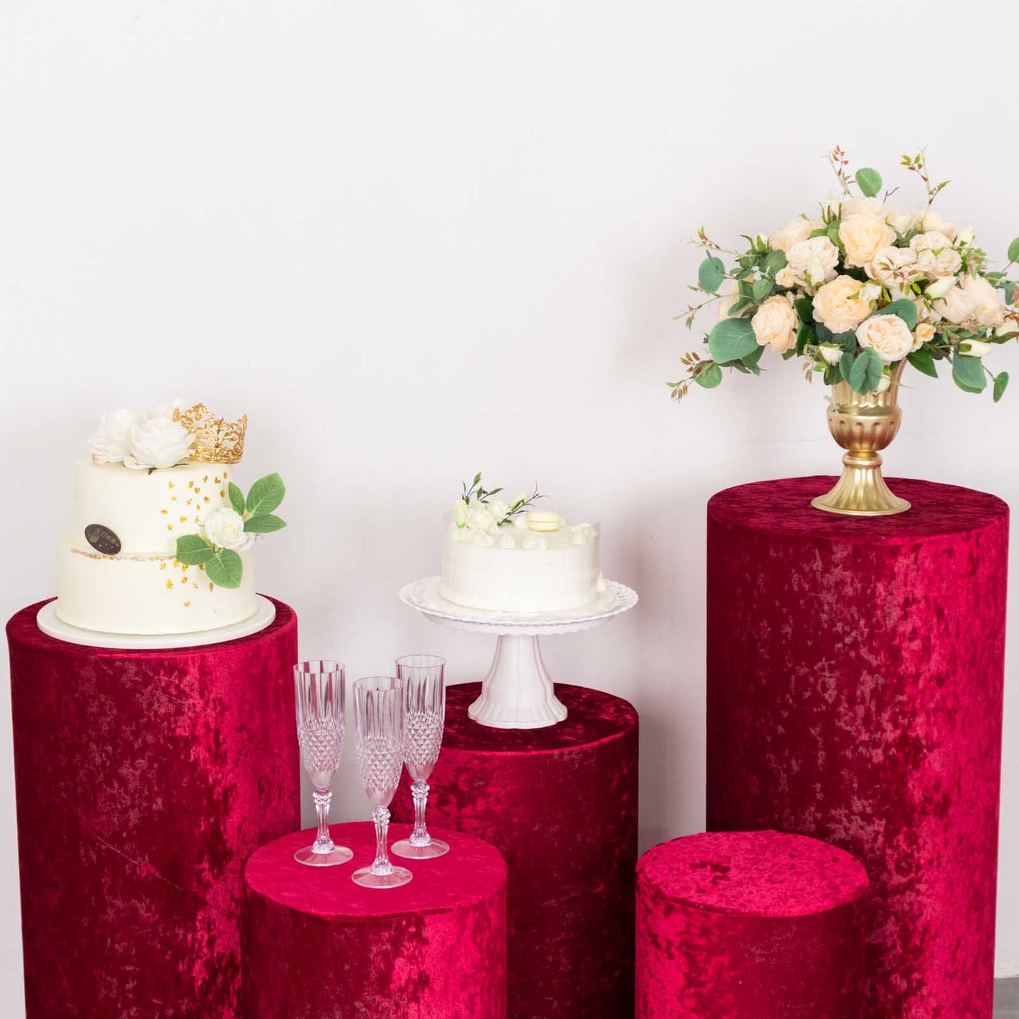 Set of 5 red crushed velvet pedestal stand covers for events.