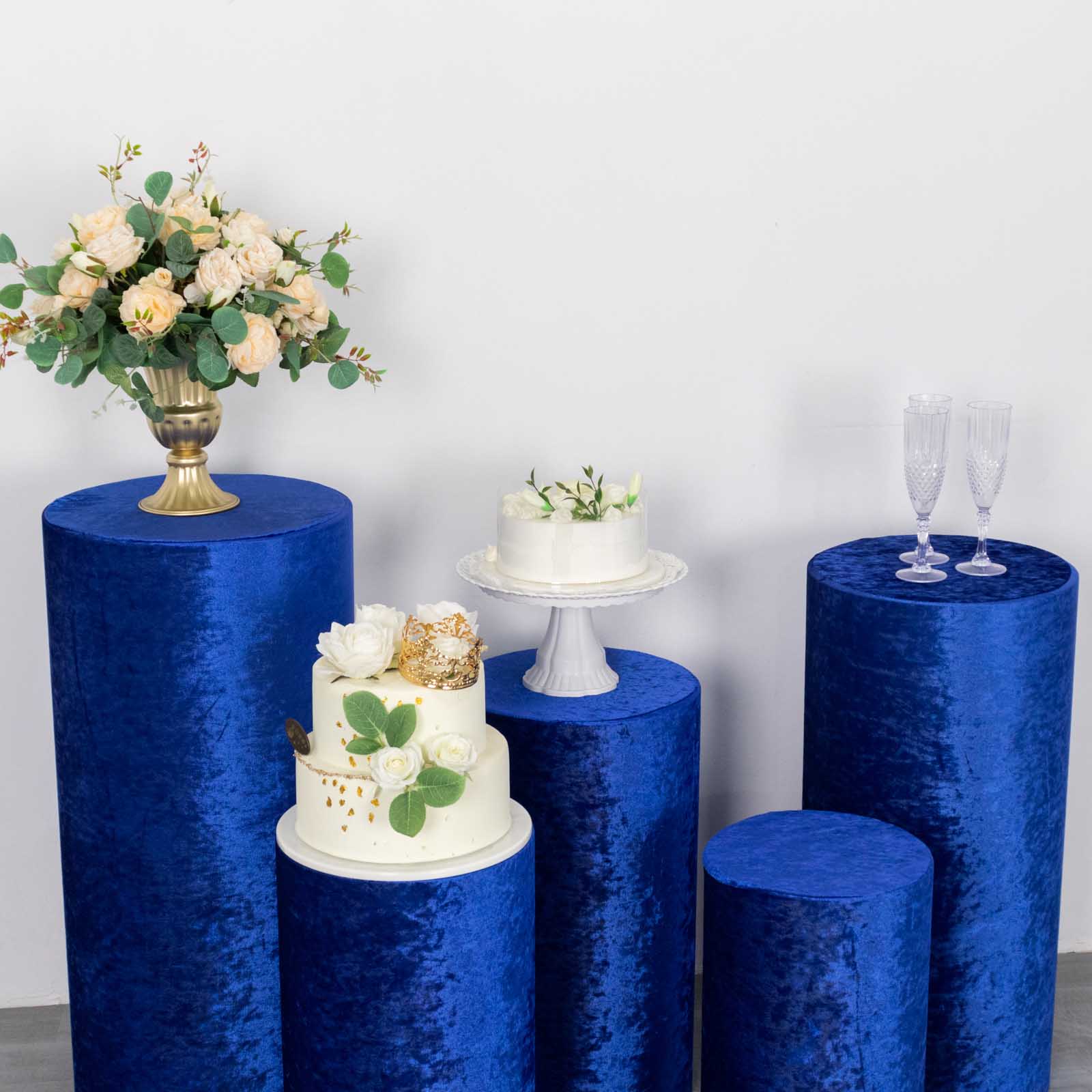 Royal blue crushed velvet pedestal stand covers set with floral and cake displays.