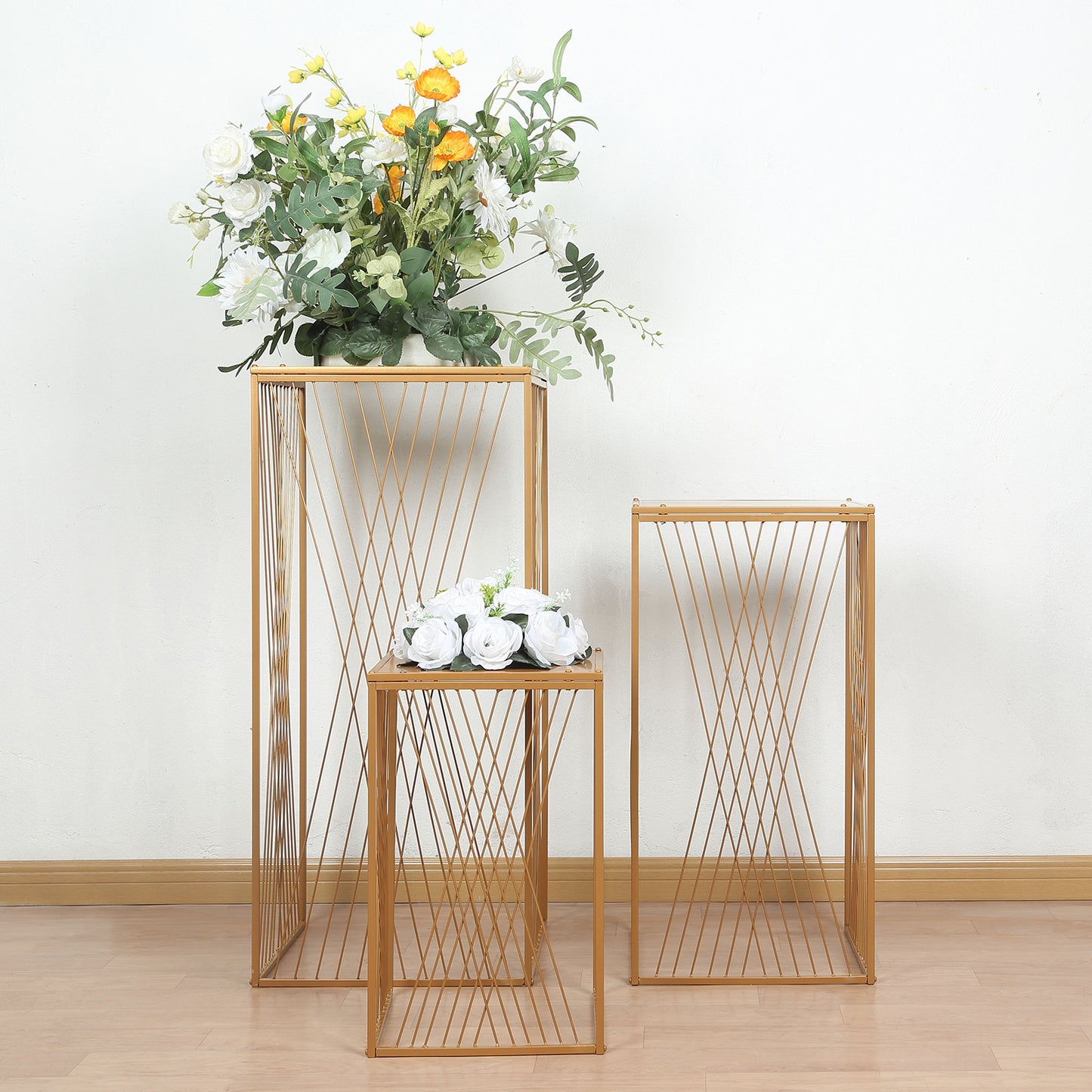 Gold metal rectangular plant stands with geometric pattern, floral displays.