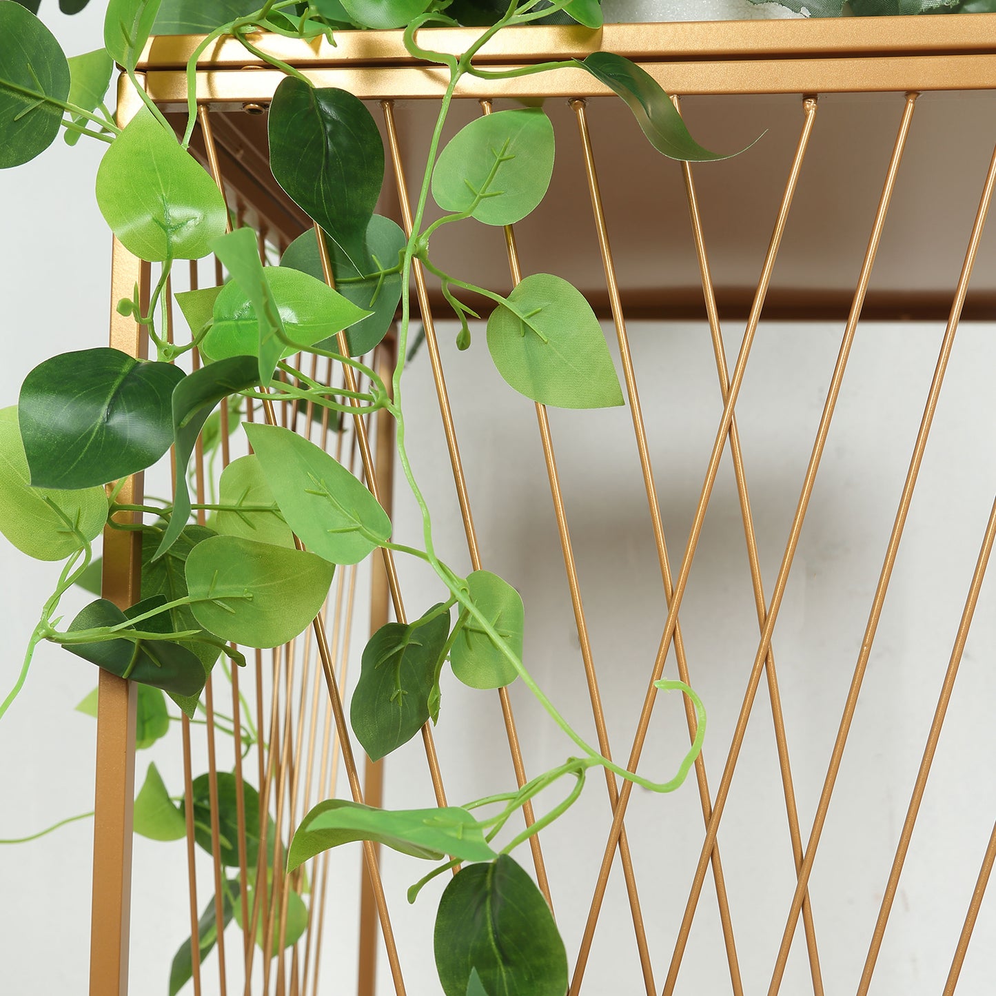 Gold metal rectangular plant stand with geometric crossed lines pattern.