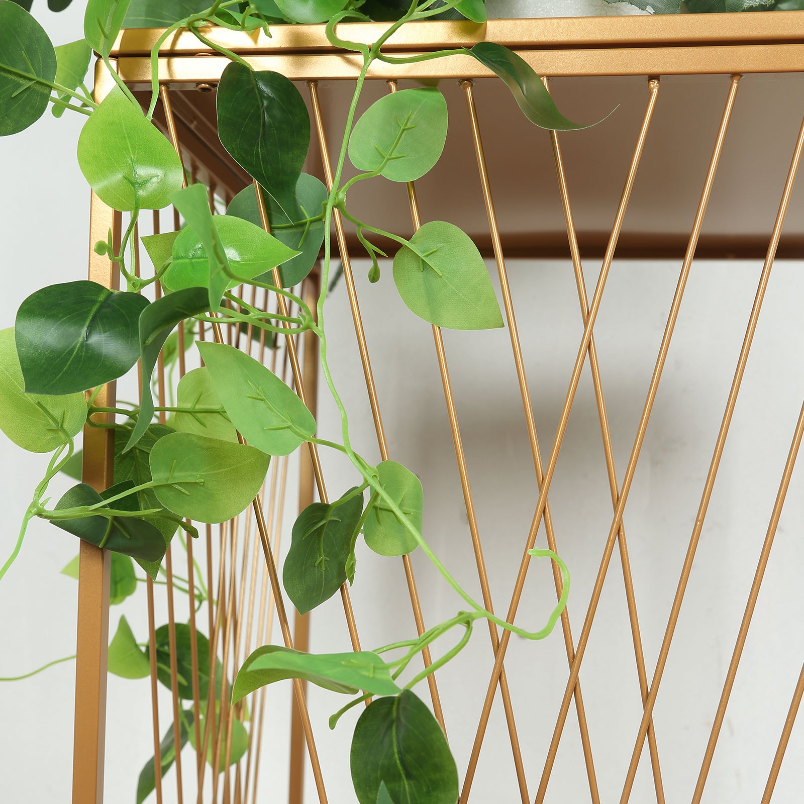 Gold metal rectangular plant stand with geometric crossed lines pattern.