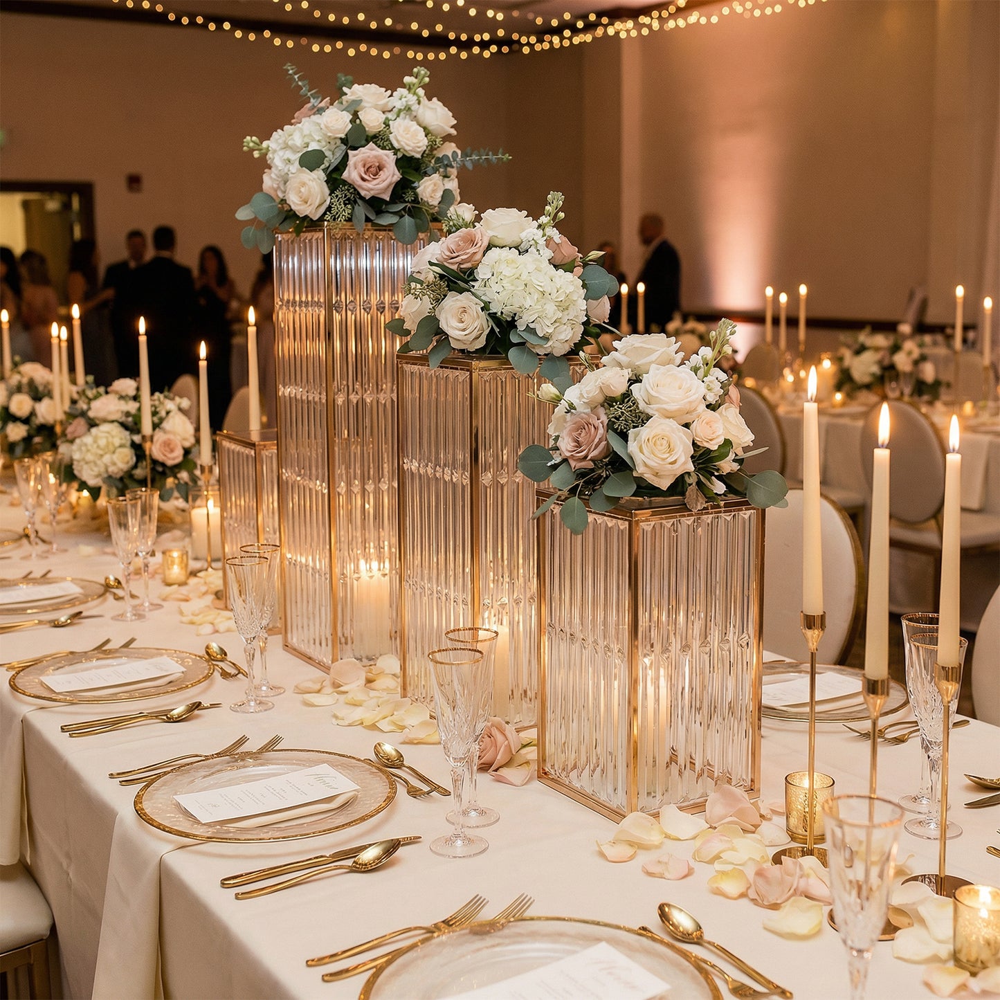 Gold pedestal stands with acrylic tops and crystal pendants for elegant floral displays.