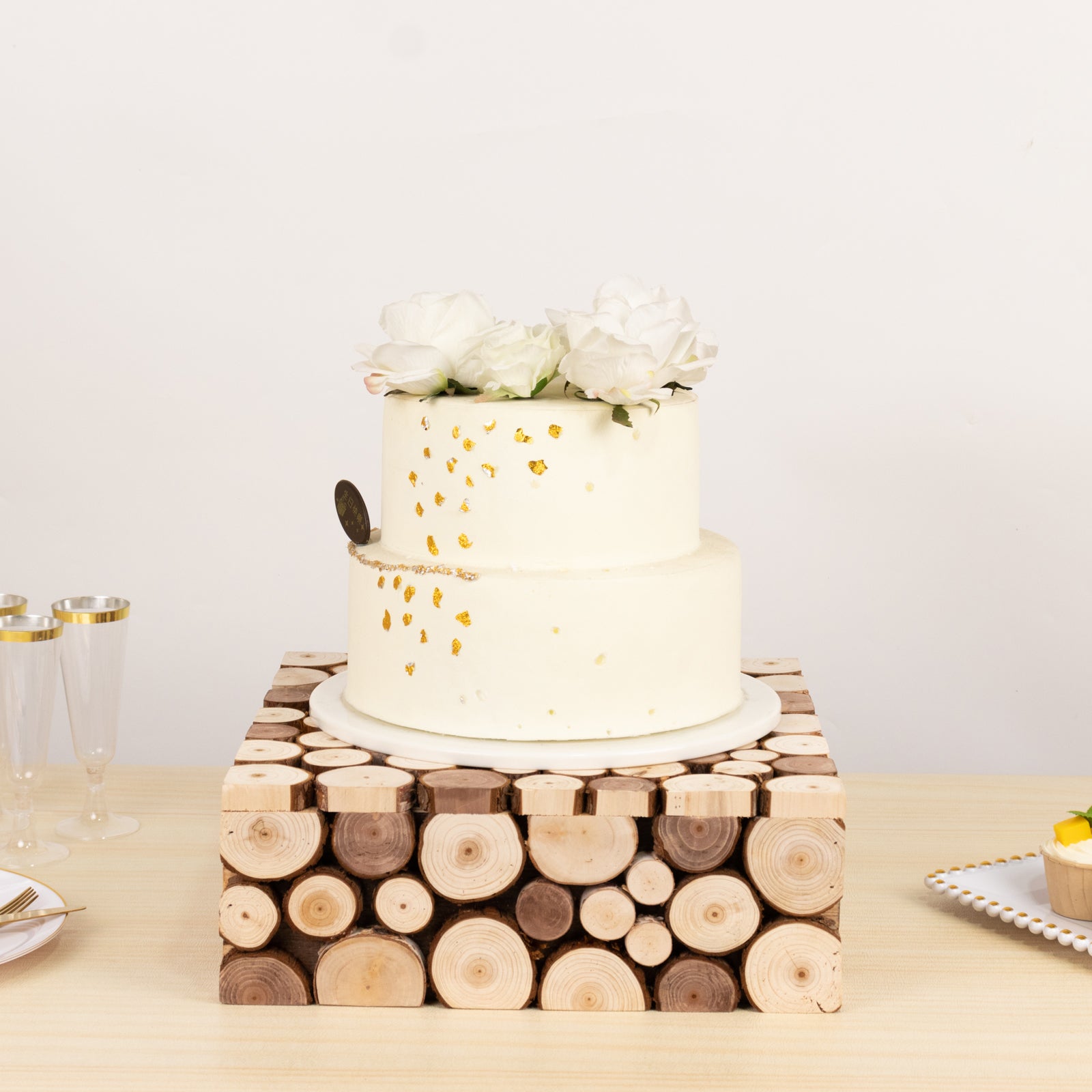 Natural wooden square riser with a white cake topped with flowers.