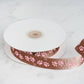 Chocolate brown pink paw print satin ribbon on a spool.