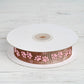 Chocolate brown and pink paw print satin ribbon on a spool.