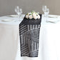 Black diamond glitz sequin table runner on a white table with floral centerpiece.