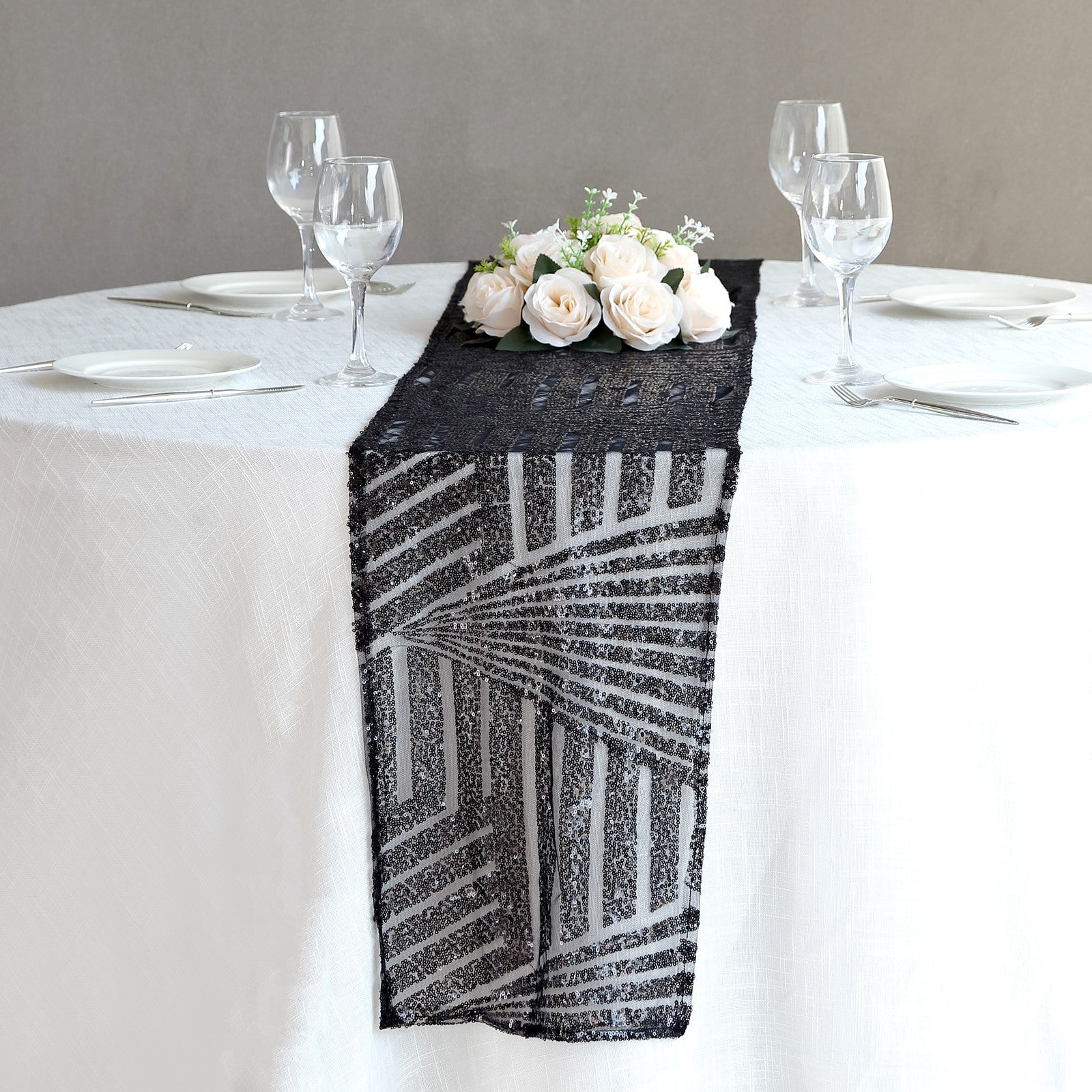 Black diamond glitz sequin table runner on a white table with floral centerpiece.
