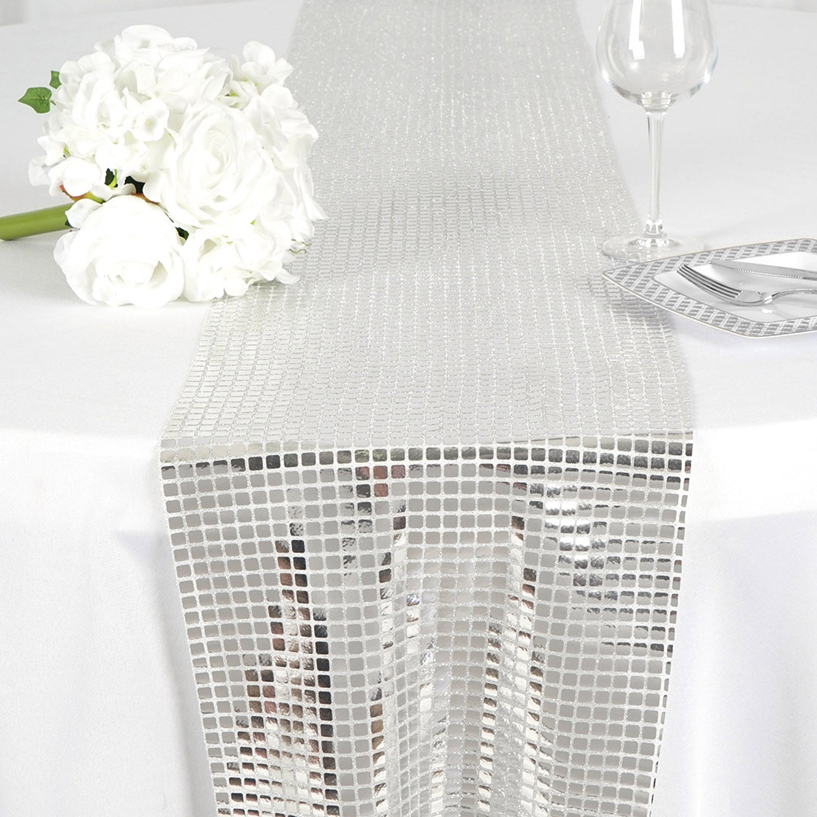 Silver mirror foil table runner on a white table setting.