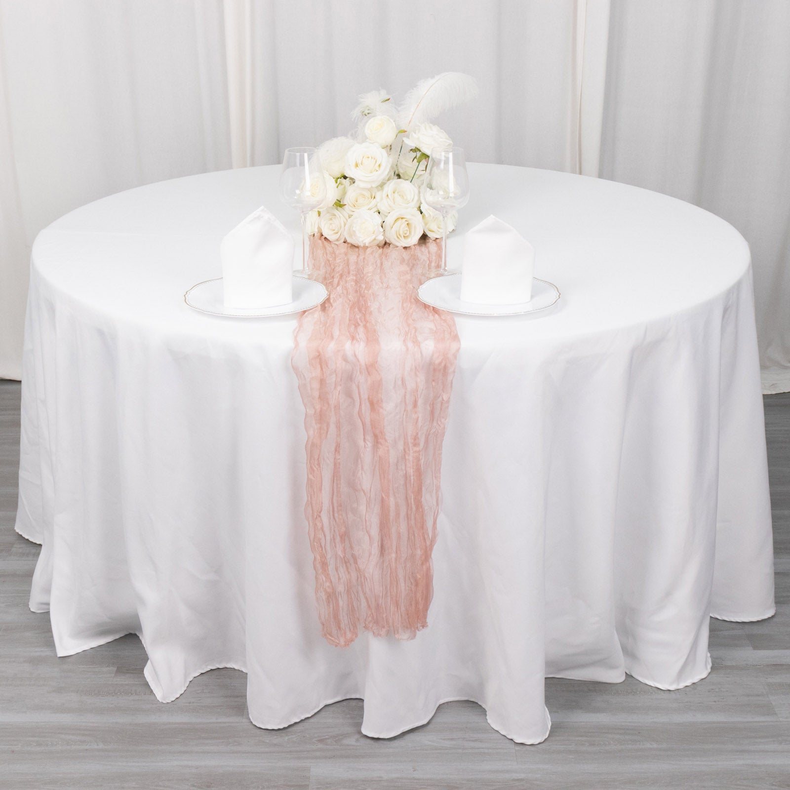 Dusty rose sheer crinkled organza table runner on a white table setting.