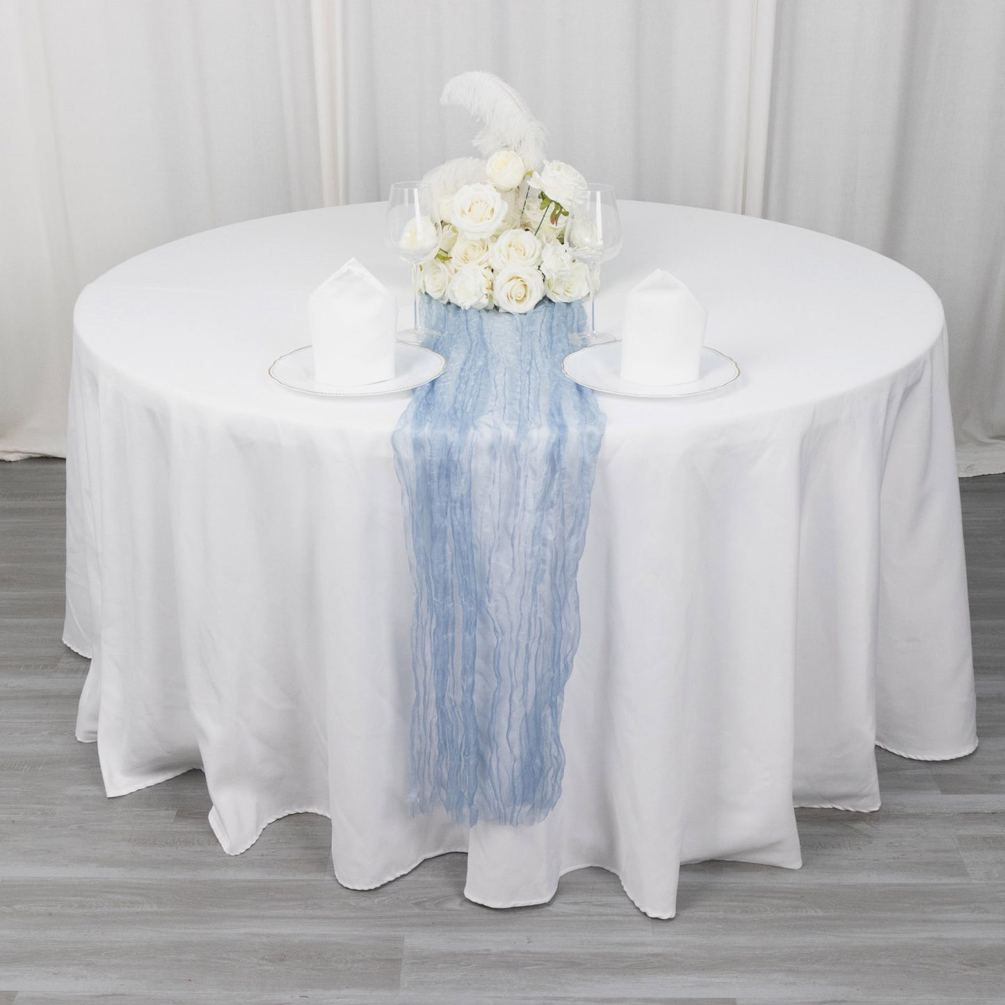 9ft dusty blue sheer crinkled organza table runner on a white table.