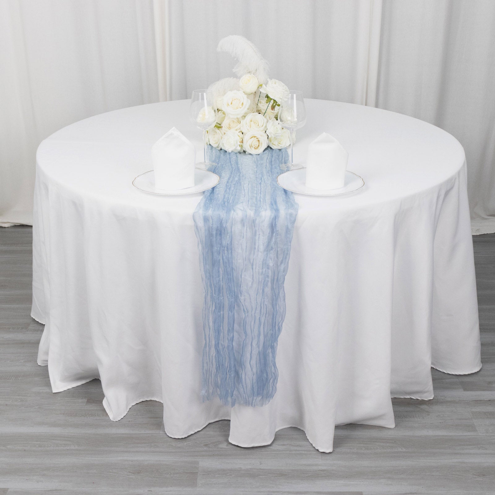 9ft dusty blue sheer crinkled organza table runner on a white table.
