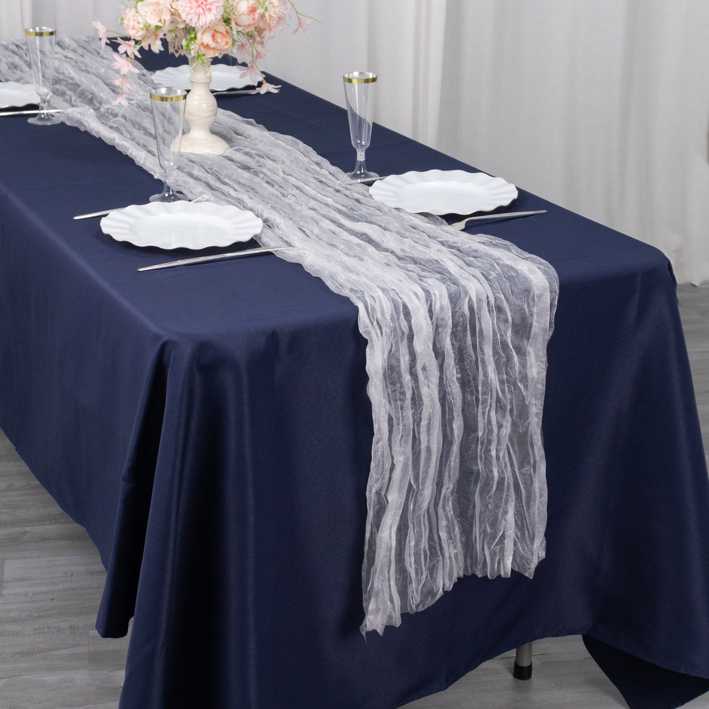 9ft sheer crinkled organza table runner in white on a navy blue table.