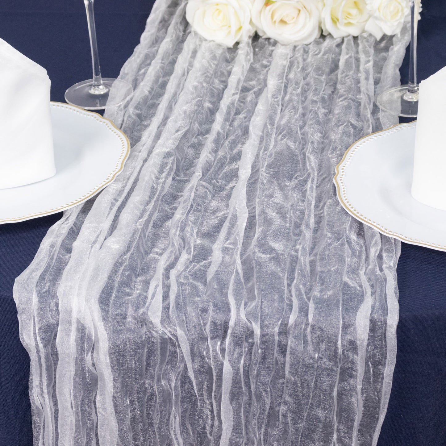 White sheer crinkled organza table runner on a navy blue table setting.