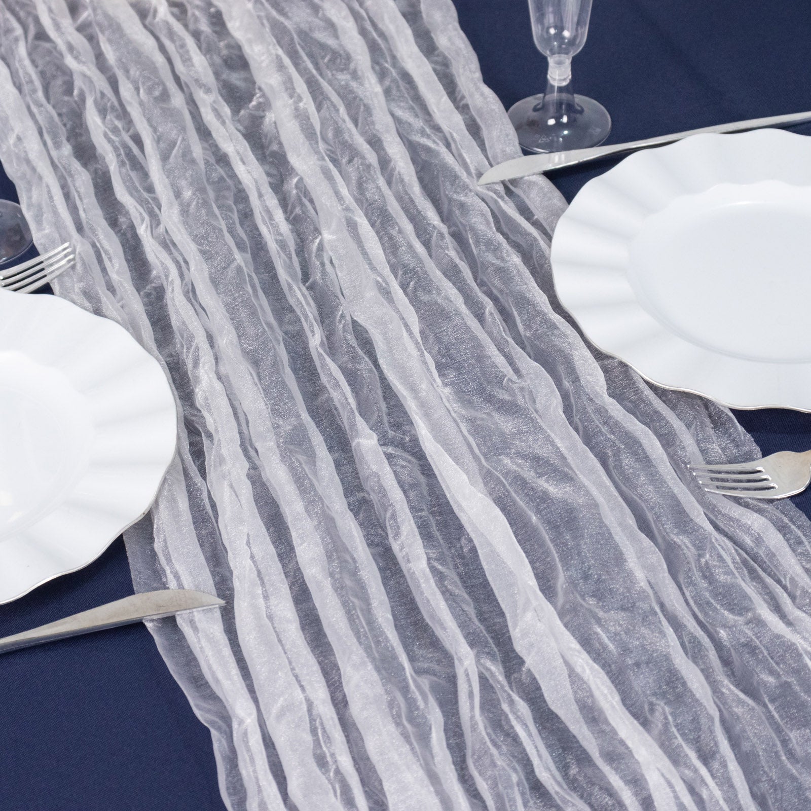 9ft white sheer crinkled organza table runner on a dark blue table setting.