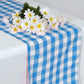 Blue and white gingham table runner with flowers on top.