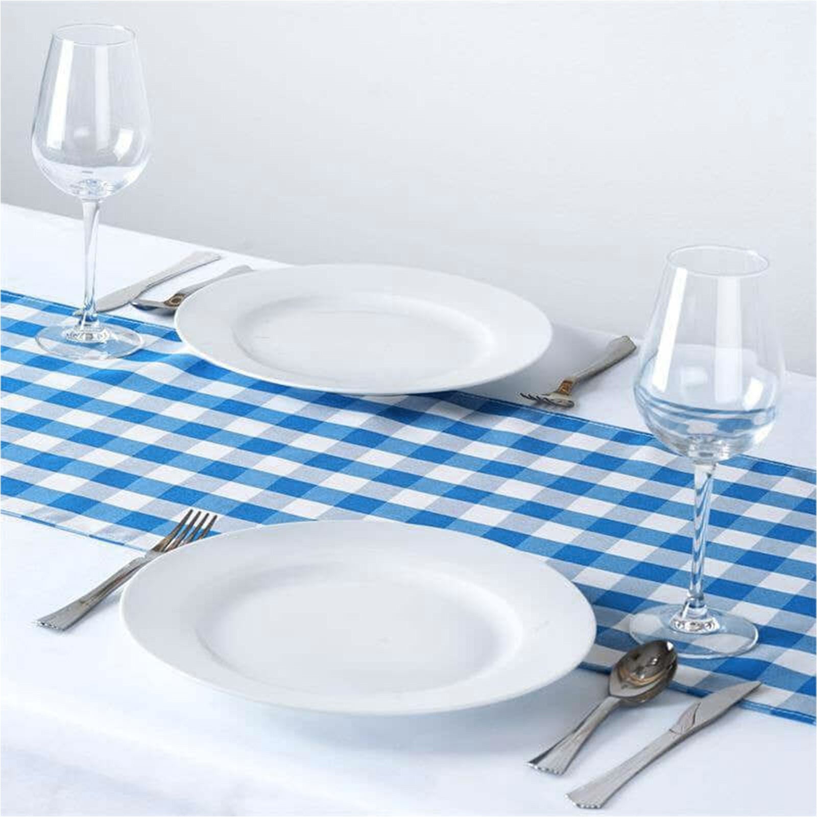 Blue and white checkered table runner on a dining table with plates and glasses.