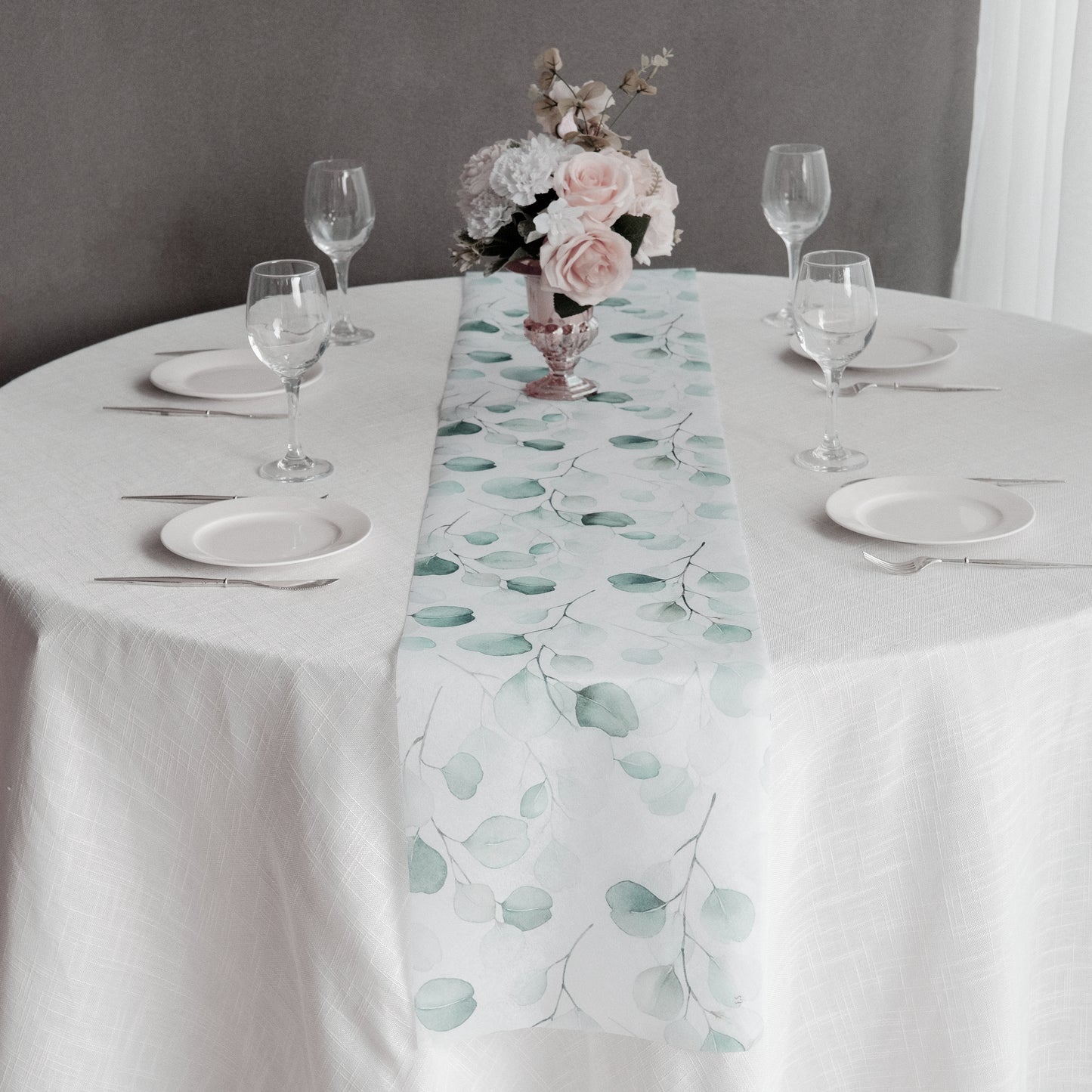 White disposable table runner with green eucalyptus leaves print on a dining table.