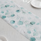 White disposable table runner with green eucalyptus leaves print.