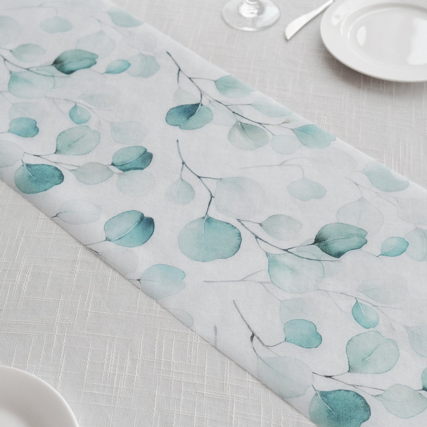 White disposable table runner with green eucalyptus leaves print.