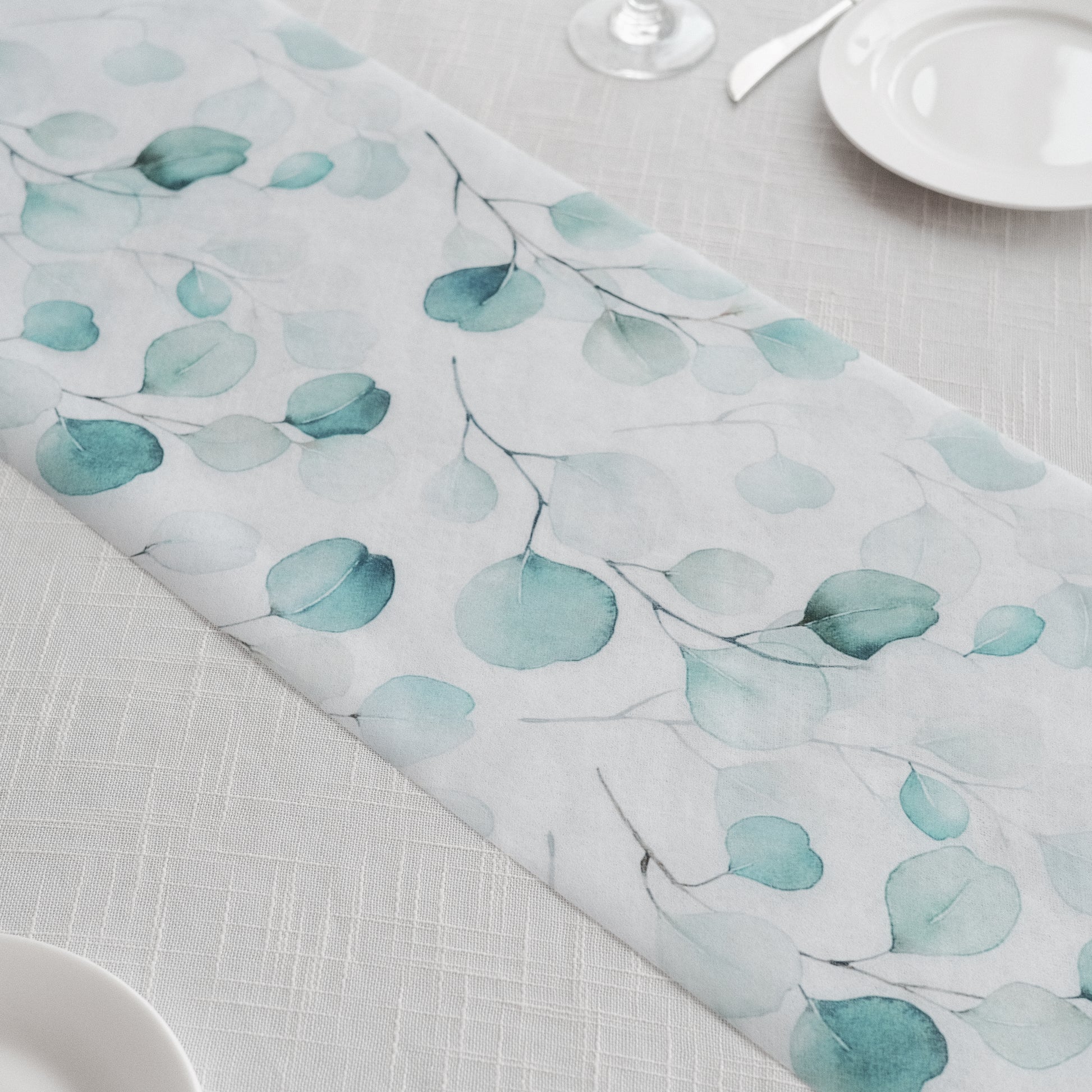 White disposable table runner with green eucalyptus leaves print.